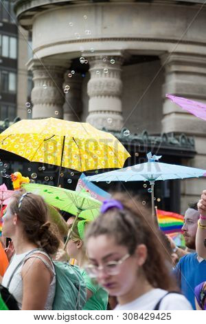 2018 JUNE 24 NEW YORK: NYC Pride March participants walk with colorful rainbow umbrellas at 23rd St and 5th Ave.