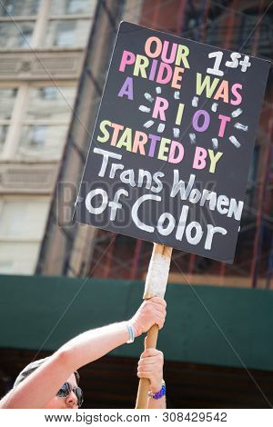 2018 JUNE 24 NEW YORK: NYC Pride March participant holds a sign that references the first parade and Stonewall Riots on the 5th Ave parade route.