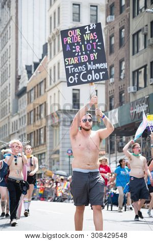2018 JUNE 24 NEW YORK: NYC Pride March participant holds a sign that references the first parade and Stonewall Riots on the 5th Ave parade route.