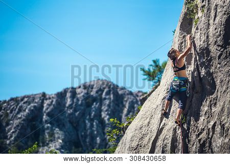 Rock Climbing And Mountaineering In The Paklenica National Park. A Woman Overcomes A Challenging Cli