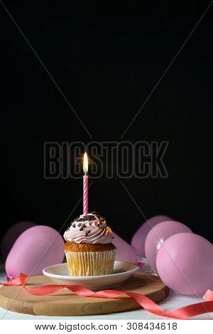Happy Brithday Cupcake With A Candle On A Black Background With Pink Balloons And Space For Text