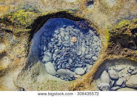 Small Black Stones In Salt Water Of Atlantic Ocean In Cliff On The Beach