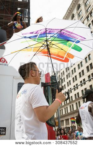 2018 JUNE 24 NEW YORK: NYC Pride March participants walk with colorful rainbow umbrellas at 23rd St and 5th Ave.