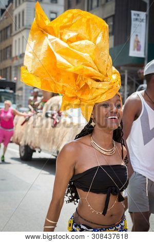 2018 JUNE 24 NEW YORK: NYC Pride March participant wearing a tribal outfit with yellow headwear walks along the 5th Ave parade route.