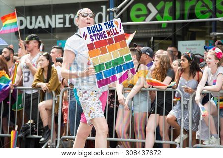 2018 JUNE 24 NEW YORK: NYC Pride March participant holds a sign that says Build The StoneWall on the 5th Ave parade route.