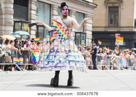 2018 JUNE 24 NEW YORK: NYC Pride March participants wearing a rainbow paper mache hoop skirt outfit walks along the 5th Ave parade route.