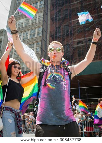 2018 JUNE 24 NEW YORK: NYC Pride March participants wave rainbow flags as they walk along the parade route on 5th Ave.
