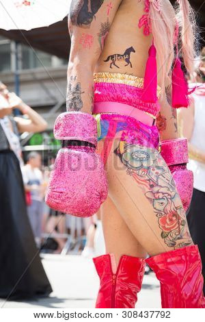 2018 JUNE 24 NEW YORK: NYC Pride March participant wearing pink boxing gloves and high heel boots walks along the 5th Ave parade route.