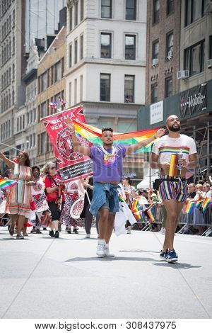 2018 JUNE 24 NEW YORK: NYC Pride March participants wave rainbow flags as they walk along the parade route on 5th Ave.