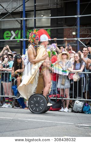 2018 JUNE 24 NEW YORK: Two NYC Pride March participants dressed in Roman gladiator outfits ride on a segway along the 5th Ave parade route.