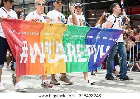 2018 JUNE 24 NEW YORK: NYC Pride March participants walk behind a We Are PVH banner on the 5th Ave parade route.