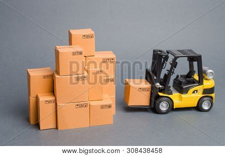 Yellow Forklift Truck Brings The Box To A Stack Of Boxes. Industry And Production. Warehouses And Tr