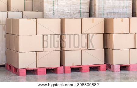 Stack Of Goods Carton Boxes On Red Pallet At Logistics Warehouse Ready For Transported