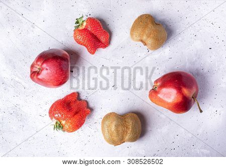 Six Ugly Fruits And Berries Laid Out In Circle On Grey Concrete Background.