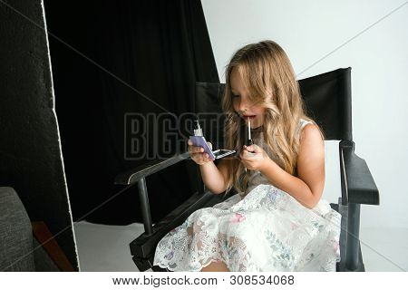 Interaction Of Children With Adult World. Cute Girl Trying To Do Bright Make Up For Being Older. Lit