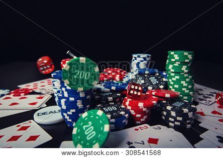 Close Up Stack Of Different Colored Poker Chips, Playing Cards And Dices Isolated Over Black Casino 