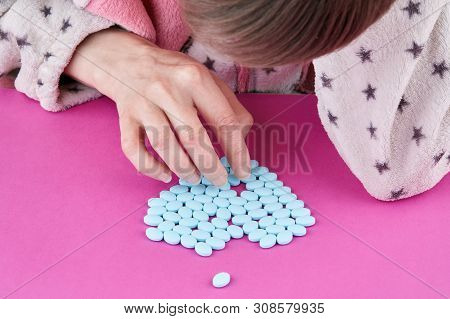 Girl Making Heart Shape Of Blue Pills.