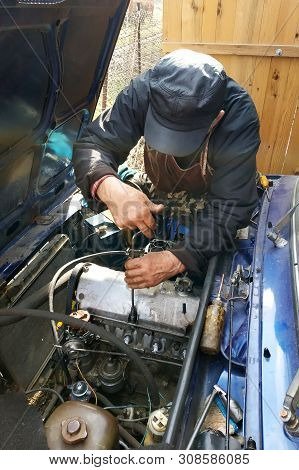 The Car Mechanic Unlocks The Motor Cover Of An Old Car And Will Repair It.