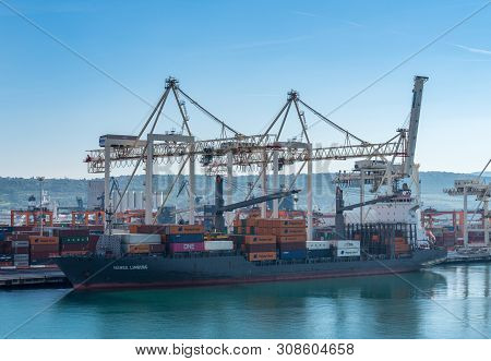 Koper, Slovenia - 24 May 2019: Cranes Load Containers Onto Ship In The Container Port Of Koper In Sl