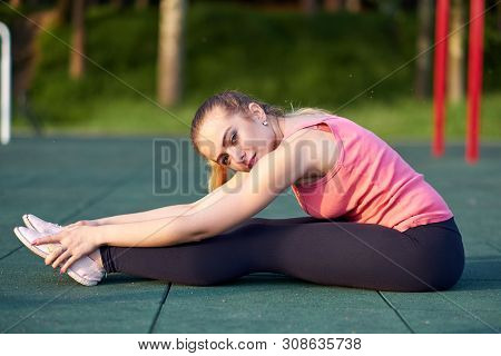 Portrait Of Fit And Sporty Young Woman Doing Stretching In Workout Sports Ground