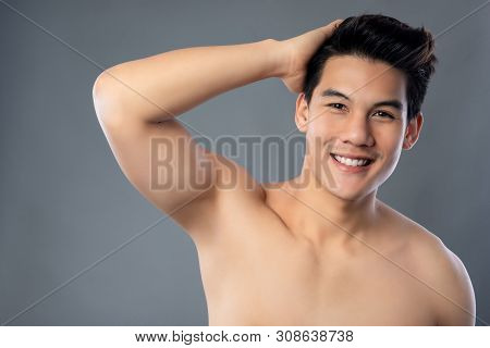 Portrait Of Smiling Shirtless Young Handsome Asian Man Posing With Hand In Hair Studio Shot Isolated