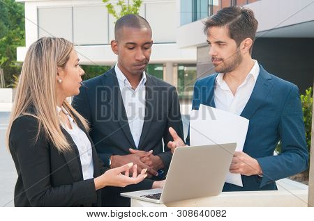 Two Business Colleagues Discussing Reports While Team Leader Making Decision. Man With Papers And Wo