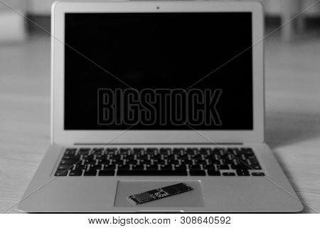 An Open Netbook Lies On A Wooden Surface In The Center. In The Zone Of Sharpness On The Trackpad, Th