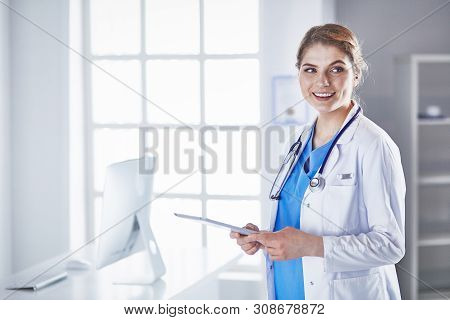 Young Woman Doctor Is Standing With Board With Clipboard Smilin