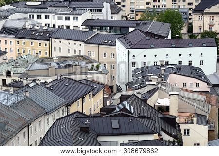 Top View Of Different Buildings Roofs With Chimneys In Typical West European City