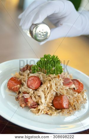 German, Polish, Austrian Cuisine Dish, Bigos - Cabbage Stewed With Meat And Sausages On A White Plat