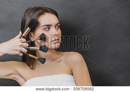 Close Up Portrait Of Beautiful Girl With Four Makeup Brushes. She Is Looking Leftwards.