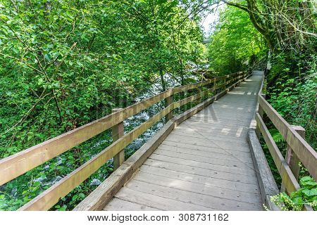 A Wooden Walkway Follows The Deschutes River In Tumwater, Washington.