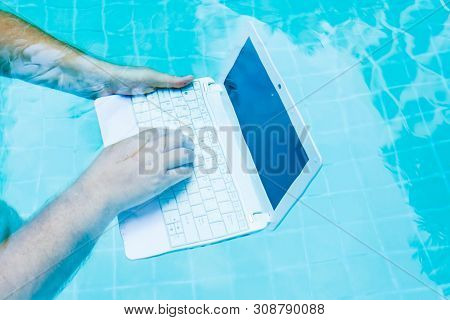 Male Works On Minicomputer Under Water. Minicomputer At The Bottom Of The Pool. The Concept Of A Lot