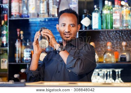 Professional African Bartender Male Holding In Hands A Shaker With A Fresh Delicious Cocktail. Barte