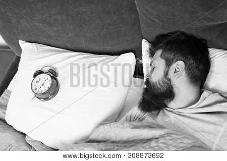 Man Bearded Hipster Sleepy Face In Bed With Alarm Clock. Problem With Early Morning Awakening. Get U