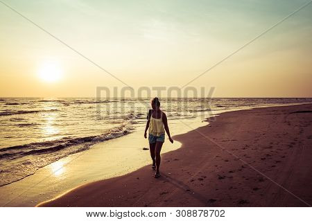 Girl Walking Along The Beach At Sunset