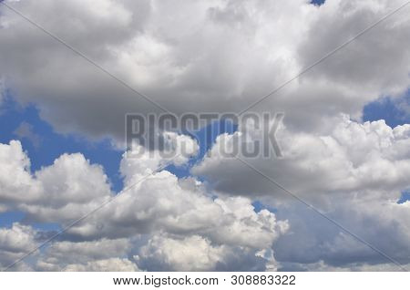 Large Fluffy Clouds Float Across The Blue Spring Sky.