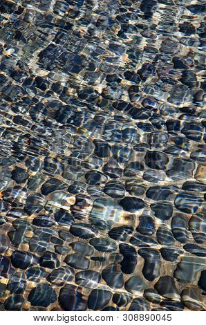 Sunny Water Ripples Over Blue Rocks.  Clear Water With Sunlit Ripple Patterns. Rocks Under Water. Ba