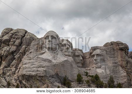 Blue Sky And White Fluffy Clouds Provide A Striking Back Drop For The Carved Faces Of Four Famous Un