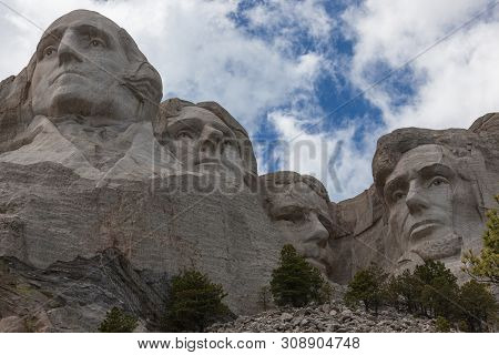 Blue Sky And White Fluffy Clouds Provide A Striking Back Drop For The Carved Faces Of Four Famous Un