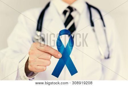 Doctor Holds Blue Ribbon,  Colon Cencer Awareness. Symbolic Concept Raising Awareness Concerns Help 