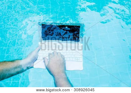 Male Works On Minicomputer Under Water. Minicomputer At The Bottom Of The Pool. The Concept Of A Lot