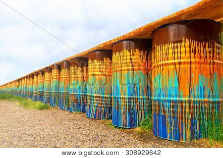 Image Of Multi-colored, Rusty And Old Oil Barrels In Piles With A Blue Sky And Sunny Day. Barrels Pe