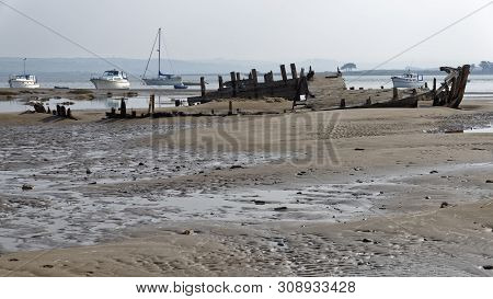 Old Fishing Boat Wreck With Modern Boats Behind, Crow Point, Braunton, North Devon, Uk