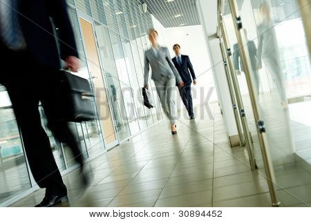 Empresários indo ao longo corredor no interior do edifício de escritórios