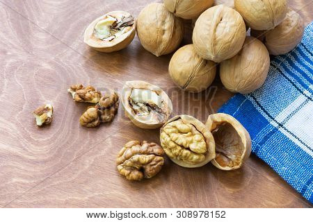 Whole Walnuts And Walnut Kernel Halves Without Shell On A Dark Wooden Table And Checkered Towel, Clo