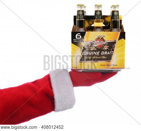IRVINE, CALIFORNIA - 4 SEPT 2020: Santa Claus holding a serving tray with a 6 pack of Miller MGD Beer over a white background.