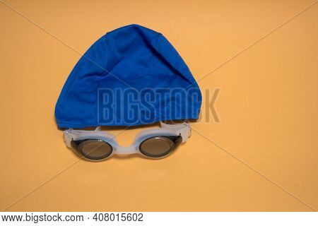 Professional White Glasses For Swimming And Blue Swimming Cap . White Swim Goggle Isolated On Yellow