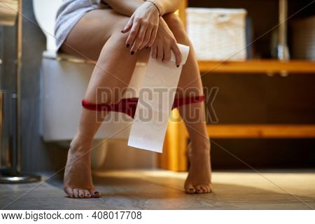 Woman sitting on the toilet having menstrual problems