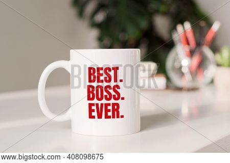 Coffee Mug With Text Best. Boss. Eyer. In Workplace Background.